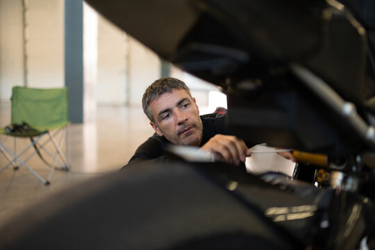 Concentrated man inspecting motorcycle in garage