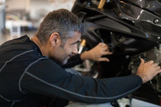 Focused motorcyclist examining motorbike before race