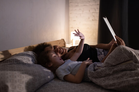 Happy black mother and daughter making video call in evening