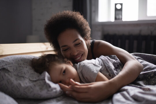 Mixed race mother hugging daughter in morning