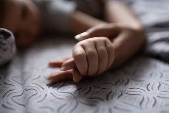 Unrecognizable child grasping finger of mother