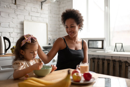 Black mother stroking daughter during breakfast