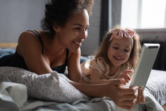 Mixed race mother and daughter playing on tablet at home