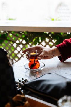 Hand reaching for Turkish tea glass on table 