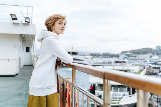 Woman standing on ferry deck looking at harbor