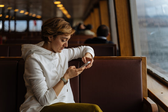 Woman using smartphone while sitting on ferry