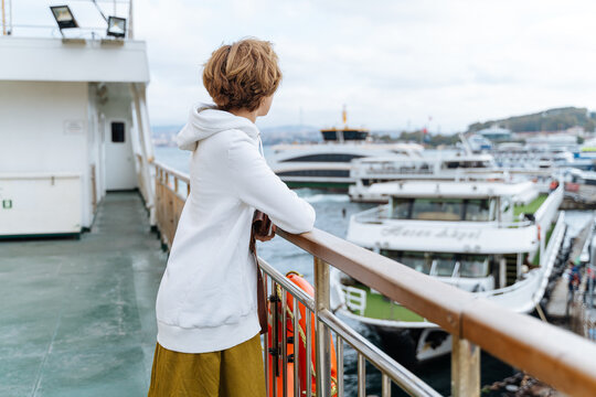 Woman looking at boats from ferry deck 