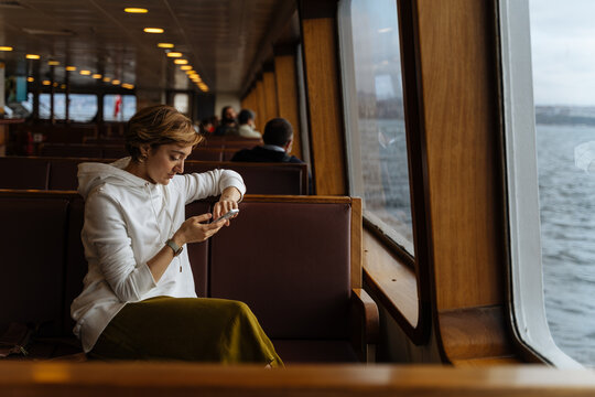 Woman using smartphone while riding on a ferry 
