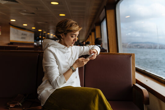 Woman checking phone while traveling on ferry