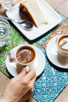 Two cups of Turkish coffee with cheesecake on a tiled table