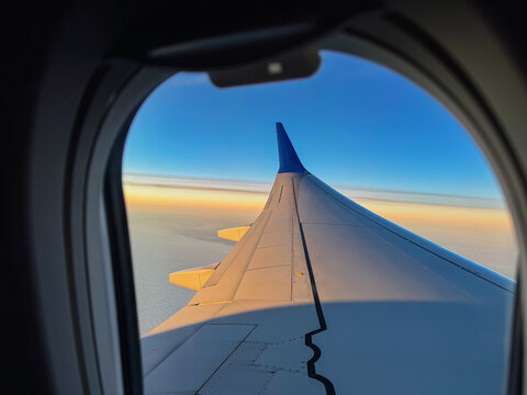 View of Airplane Wing and Sky During Flight in Evening Light