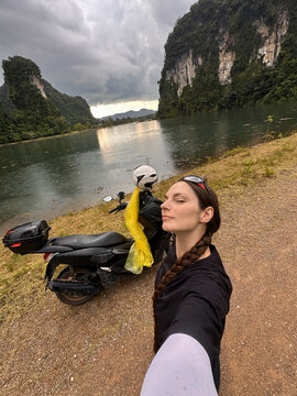 Woman next to her scooter by the lake