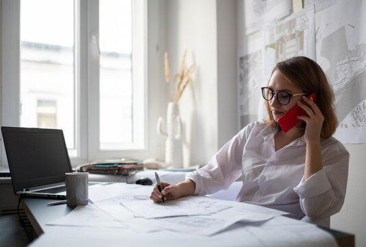 Female architect speaking with client on smartphone