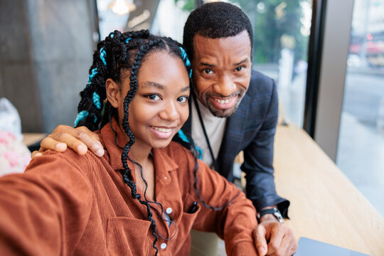 Smiling father and daughter pose for a selfie indoors.