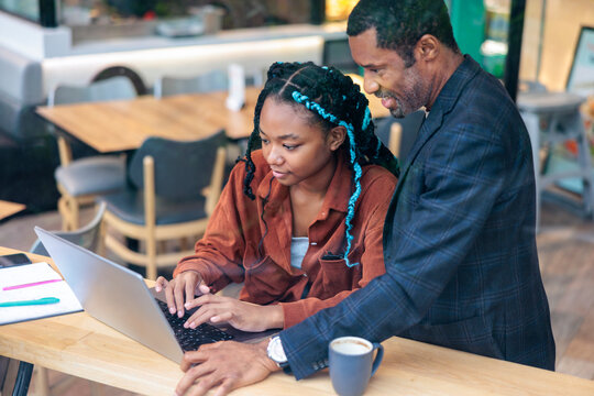 Mentoring, Man helps young woman with laptop work.