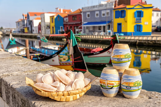 Ovos moles de Aveiro tradicionais, doces em forma de concha com barcos moliceiros, casas coloridas e a ria de Aveiro como cen&aacute;rio de fundo