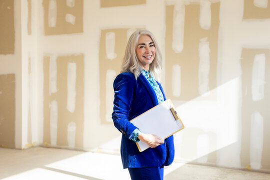 portrait of businesswoman holding documents smiling at camera