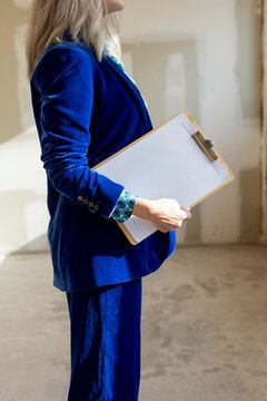 Anonymous female realtor holding documents in raw space