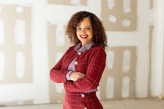portrait of smiling businesswoman in red suit over unpainted wall