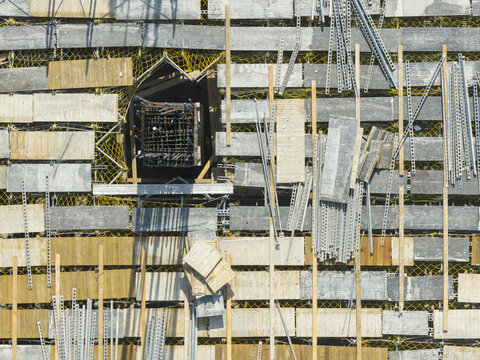 Aerial view of building construction and formwork with wooden planks, metal scaffolding, and a central rebar column in New Taipei, Taiwan.