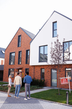Back view of black male realtor showing modern townhouse to couple