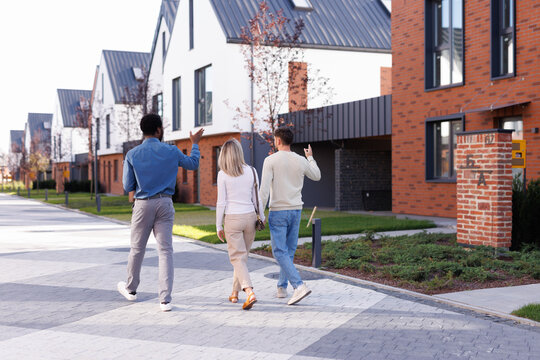 Realtor and couple going, pointing and looking at townhouse complex