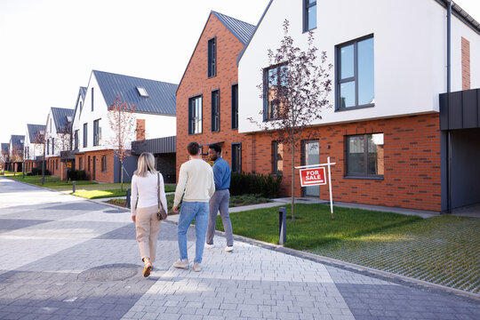 Black male realtor and couple going and looking at townhouse complex