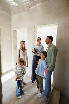 Adult female realtor showing new spacious house inside to young family