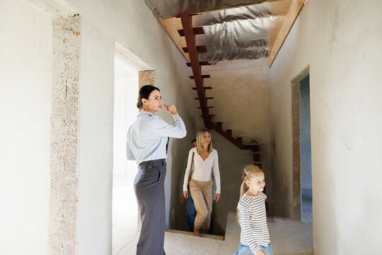 Realtor showing new empty house inside to family going up on staircase