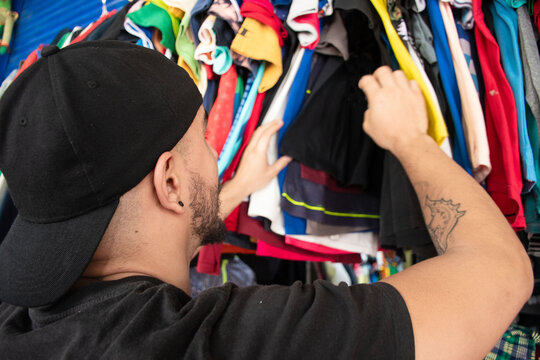 Man Browsing Through Clothing Rack at Local Thrift Store