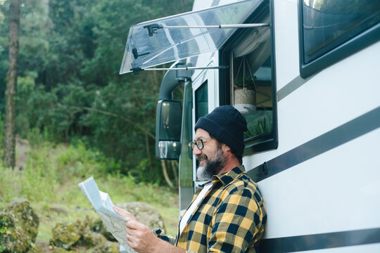 Man reading a map beside his camper van during a relaxed forest road trip