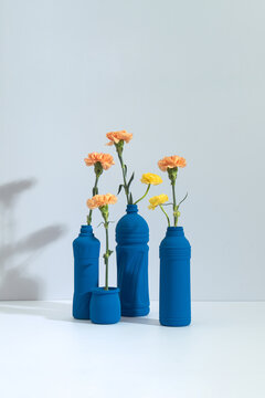 Blue painted plastic bottles repurposed as minimalist vases