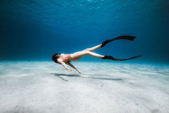 Artistic freediver creating graceful underwater movement