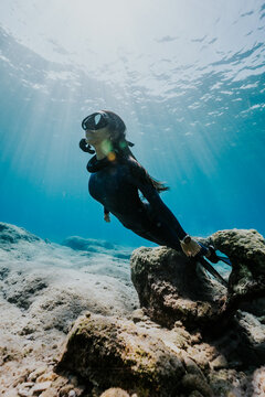 Freediver exploring clear shallow waters near rocky coast