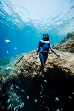 female freediver ascending peacefully from a cave