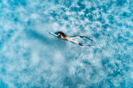 playful freediver moving across sandy seabed