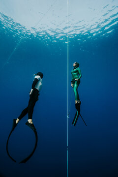 female elite freediver ascending with safety diver