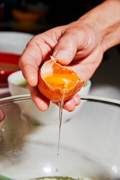 a man cracks an egg while separating yolk and white