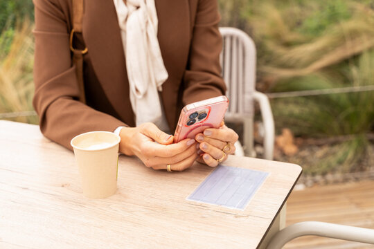 Person Using a Smartphone While Seated at an Outdoor Table