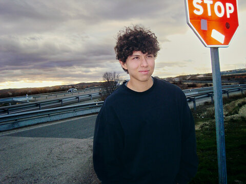 Person Standing Near Road Sign at Sunset