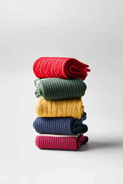 Colorful socks stacked on a plain surface