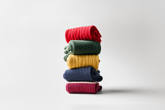 Colorful socks arranged in a stack on a plain surface
