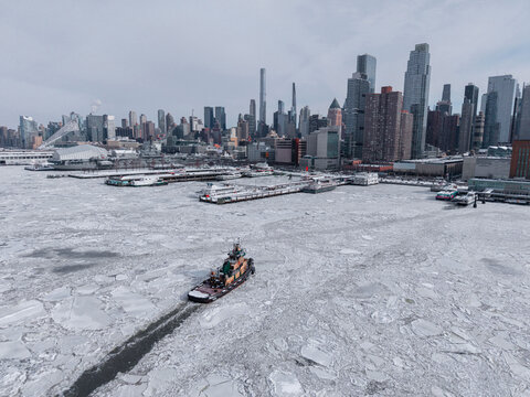 Tugboat arriving at Manhattan piers in icy river
