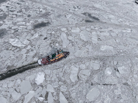 Tugboat pushing through dense cracked river ice
