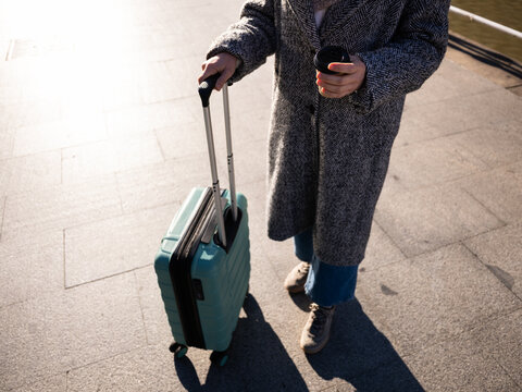 Woman traveling walking with suitcase and coffee
