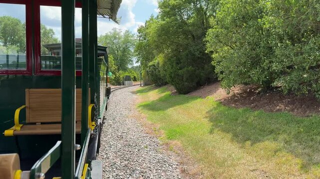 A vintage train follows curved railway tracks surrounded by green trees. The image represents scenic travel and outdoor transportation.