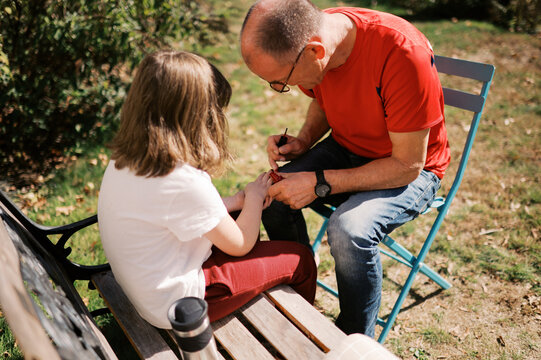grandfather painting nails of granddaughter 