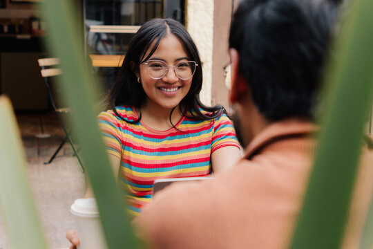 Smiling young woman looking at her partner at an outdoor cafe