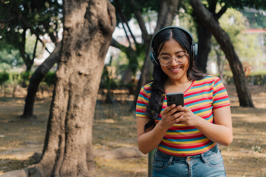 Young woman with glasses using a phone and wearing headphones