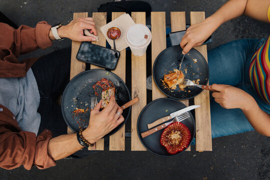 Top view of a man and woman eating bread and coffee at a wood table